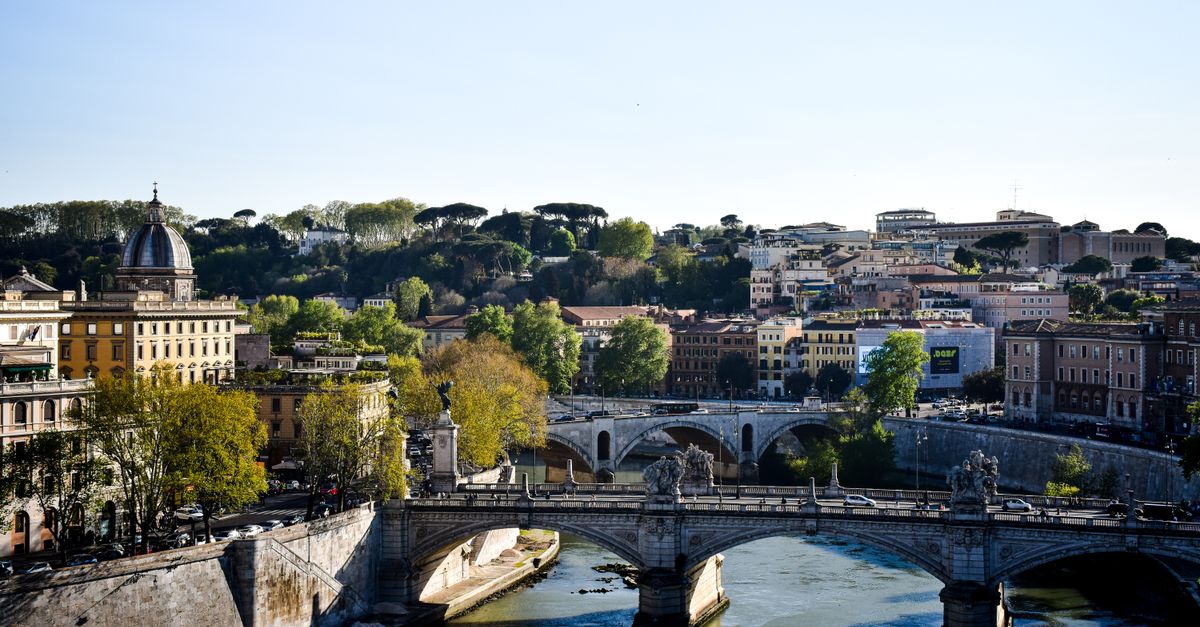 Beautiful view of Ponte Sant'Angelo spanning the Tiber River in Rome, Italy under a clear sky.